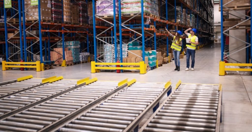 2 people in a large warehouse to describe What is a conveyor system